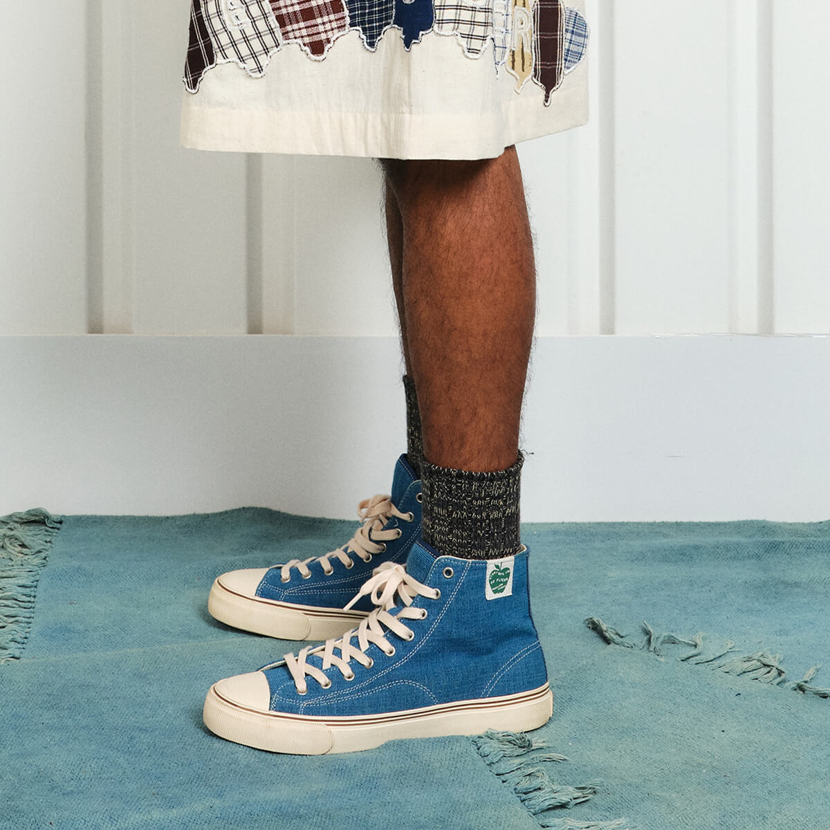 A person standing on a rug wearing indigo high-top sneakers.