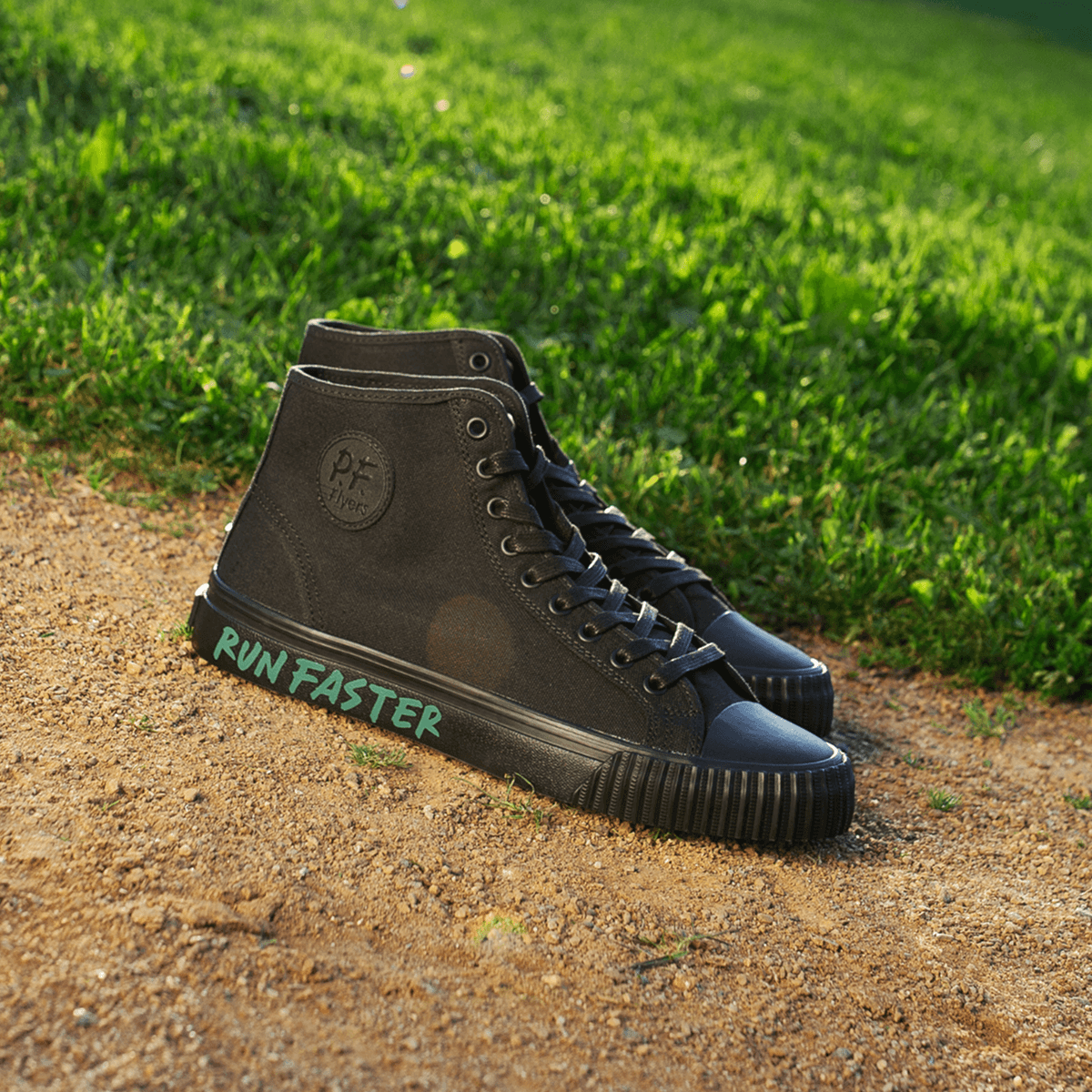 Black high-top sneakers with 'Run Faster' text on a grassy and dirt path background