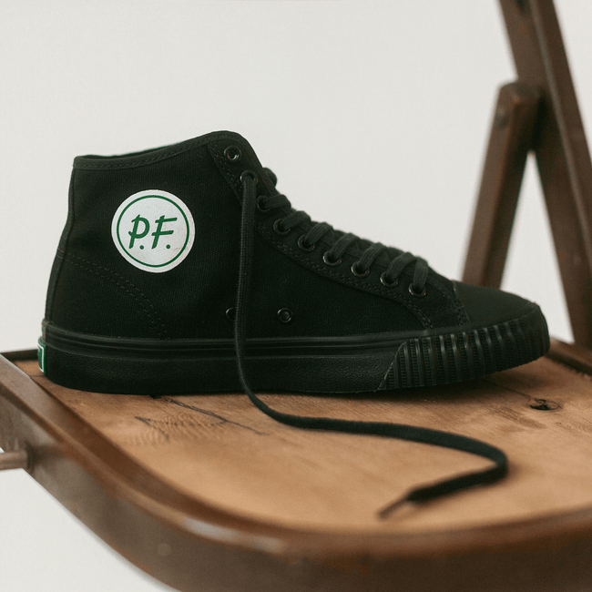 Close up of a black high-top sneaker on a wooden chair.