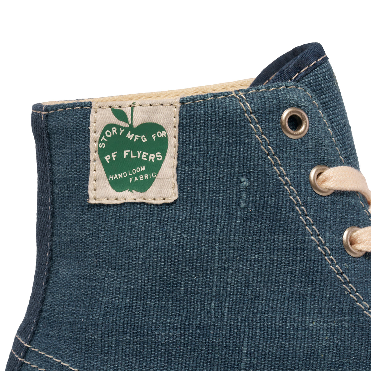 Close-up of a 'Story MFG for P.F. Flyers' label on an indigo high-top sneaker.