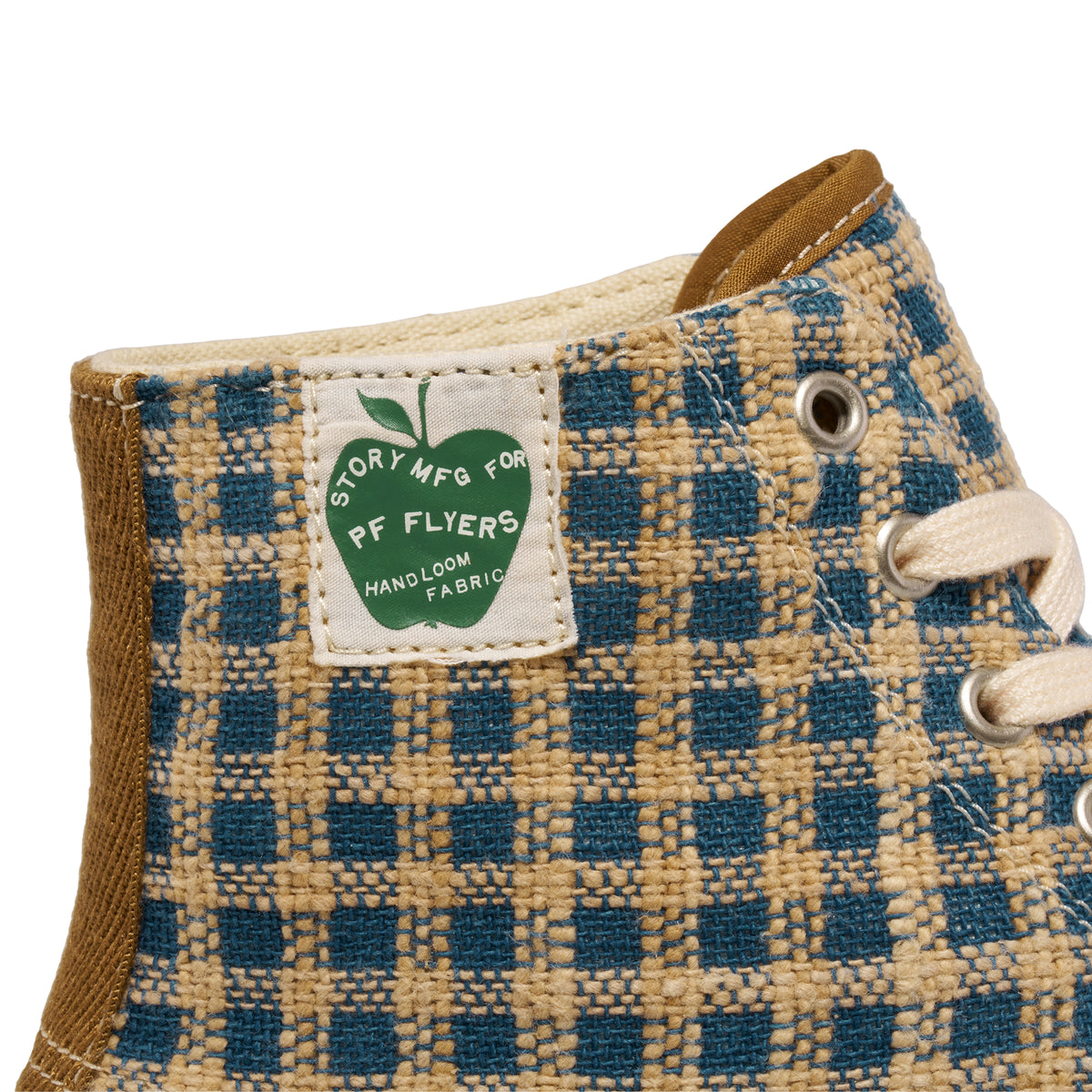 Close-up of a 'Story MFG for P.F. Flyers' label on a plaid high-top sneaker
