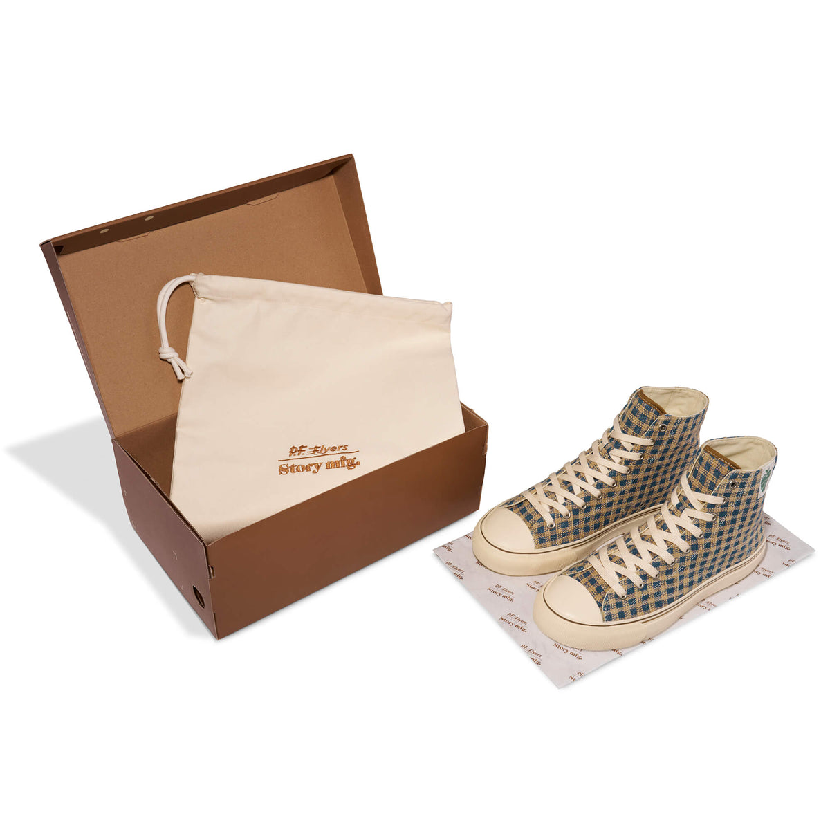 A pair of indigo and brown high-top sneakers next to a cream dust bag and brown shoe box.