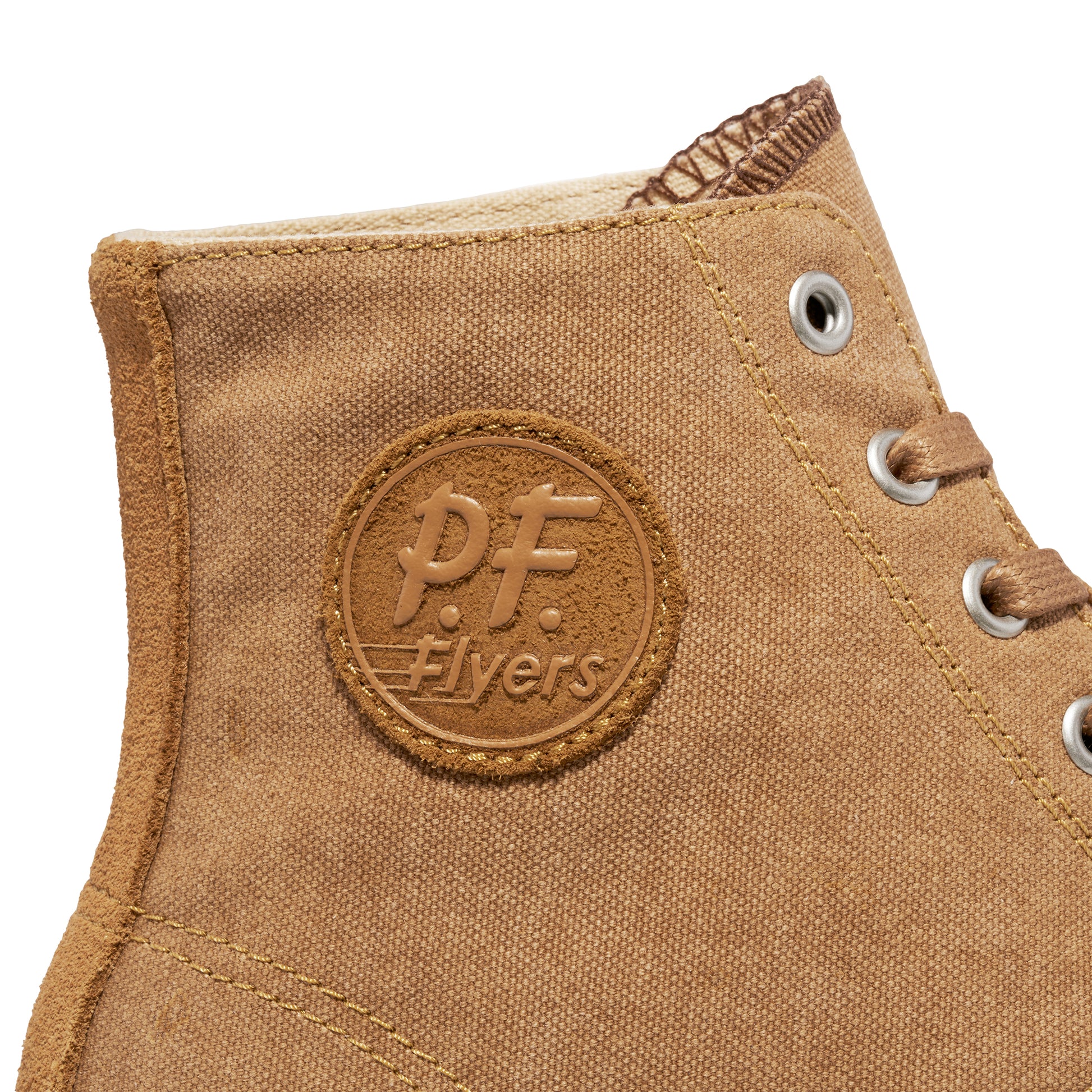 Close-up of a tan P.F. Flyers logo on a high-top sneaker against a white background.