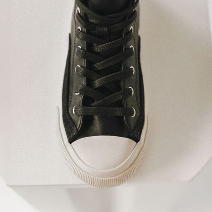 Black high-top leather sneaker with white sole on a light gray background