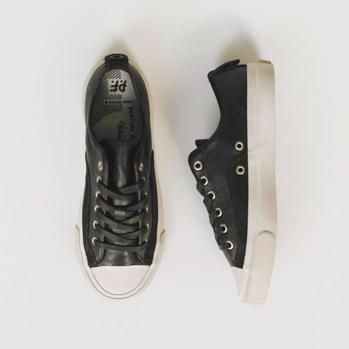 Black sneakers with white soles on a light gray background