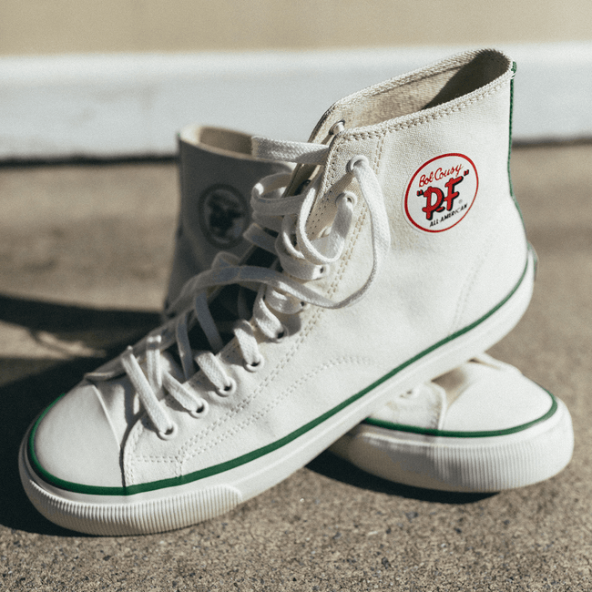 White high-top sneakers on a concrete surface.