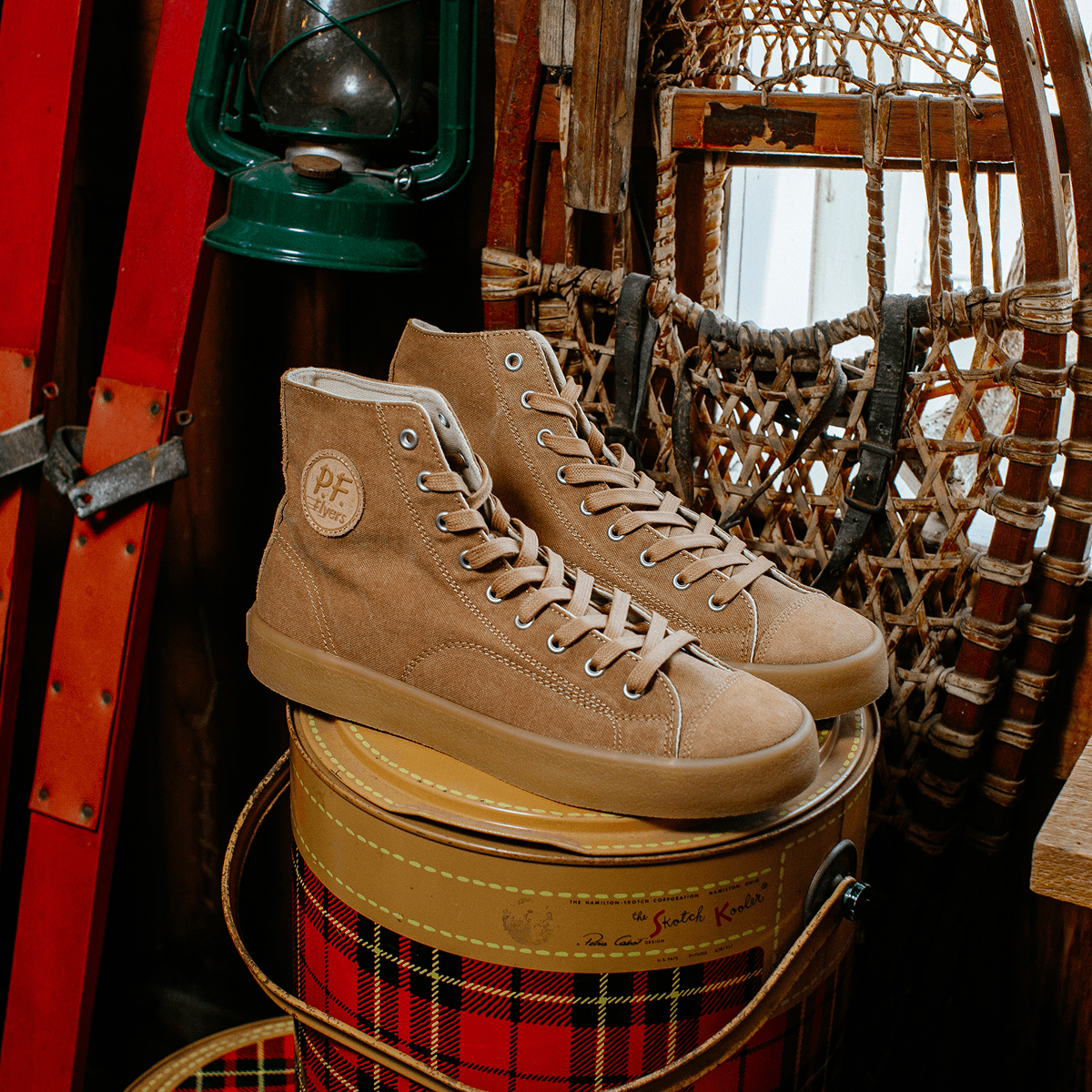 Tan high-top sneakers on a plaid barrel with rustic background.