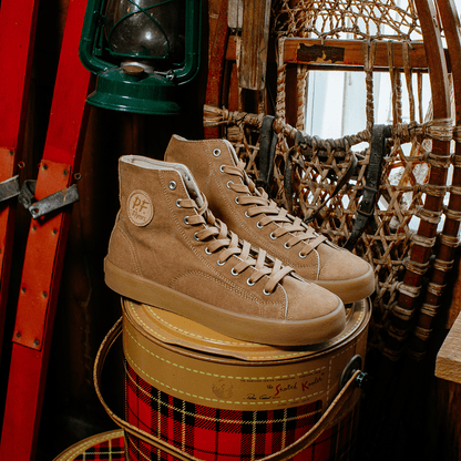 Tan high-top sneakers on a plaid barrel with rustic background.