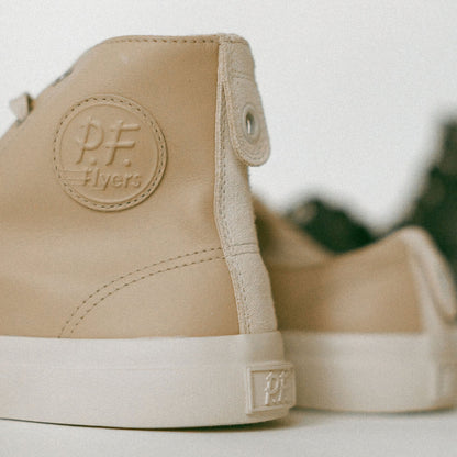 Beige high-top sneakers with 'P.F. Flyers' logo on a blurred background