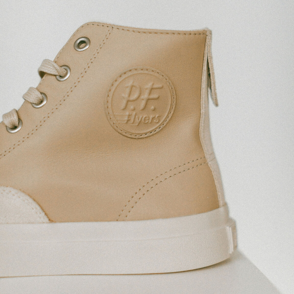 Beige high-top sneaker with a visible  P.F. brand logo on a light background