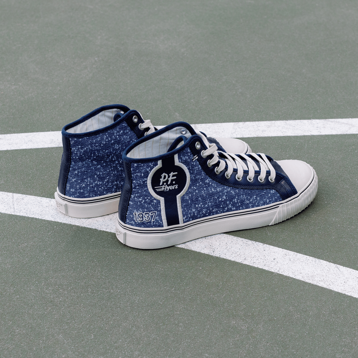 Blue navy high-top sneakers with white soles on a court.