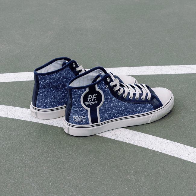 Blue navy high-top sneakers with white soles on a court.