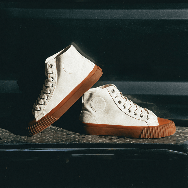 White high-top sneakers with brown soles posed on a truck bumper.