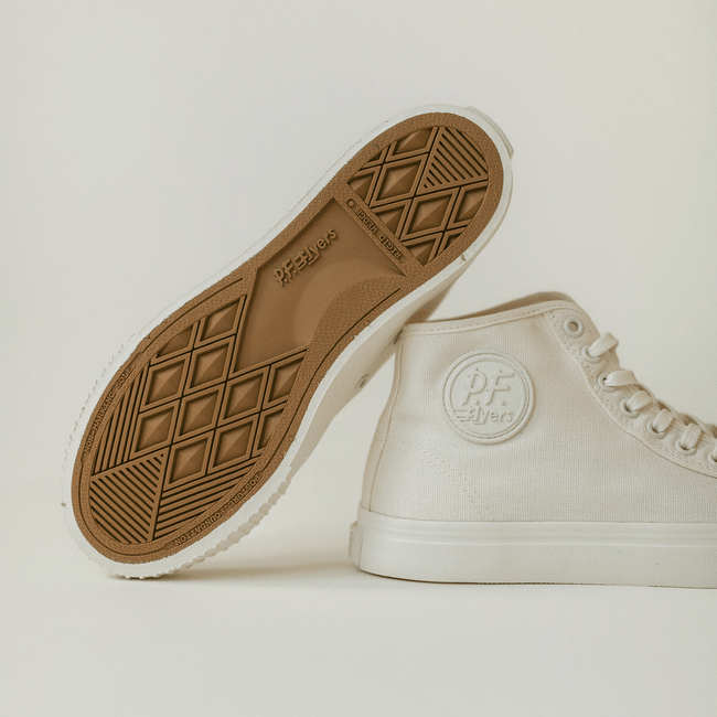 White high-top sneakers with brown soles on a light background.