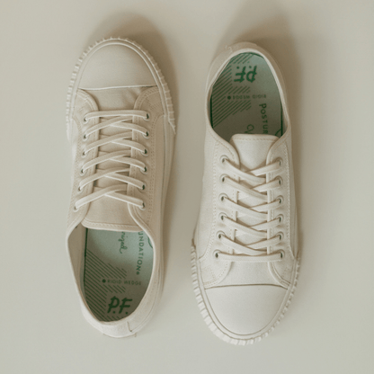 Pair of white low-top sneakers on a light background.