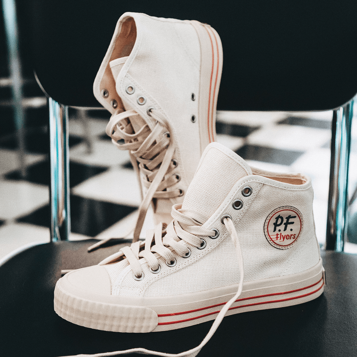 White high-top sneakers with red accents posed on a diner chair.
