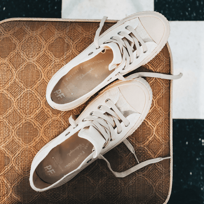 White low-top sneakers with red accents on a diner chair.