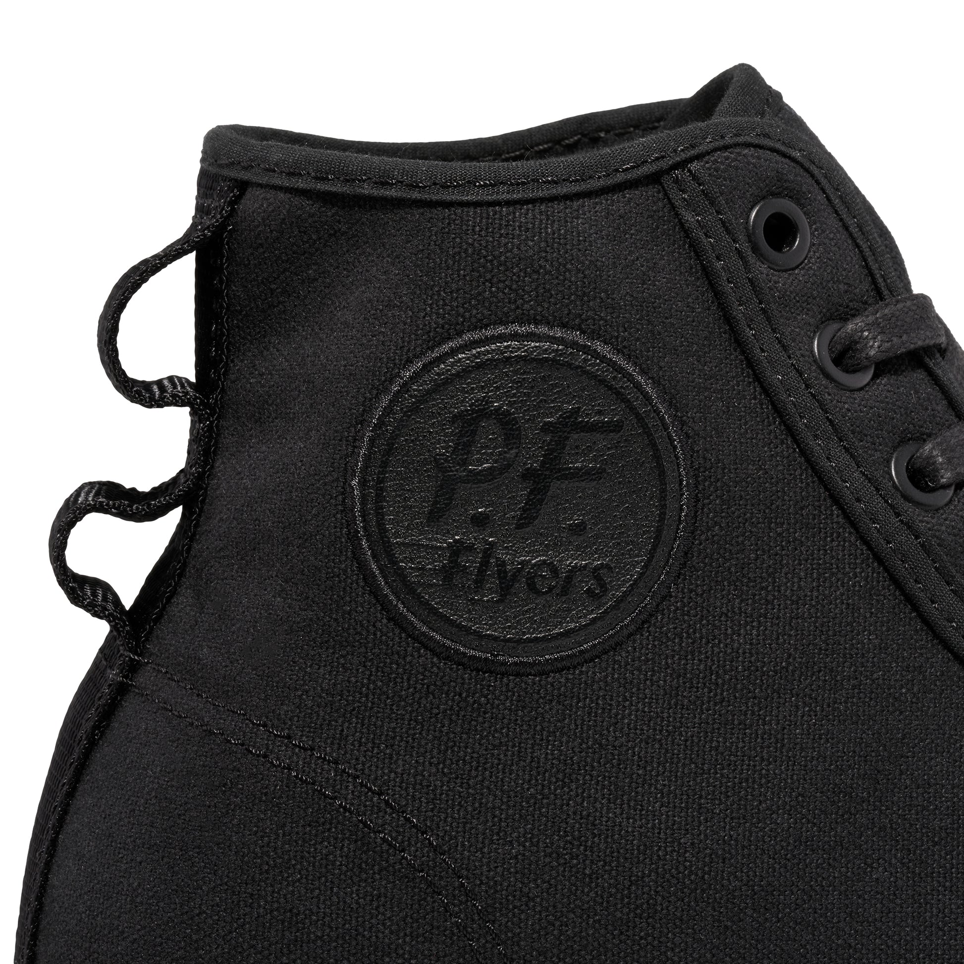 Close-up of a black P.F. Flyers logo on a high-top sneaker against a white background.