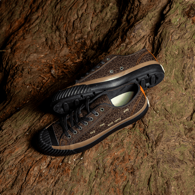 Brown low-top sneakers with black soles on a natural wooden surface.