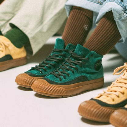Green and black high-top sneakers worn with matching socks on a light background