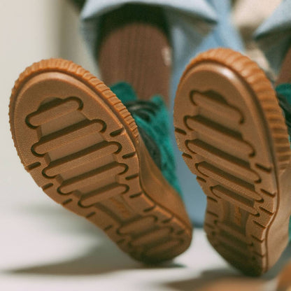 Close-up of green shoes with textured soles on a light background