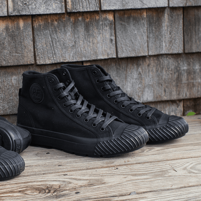 Black high-top sneakers on a wooden porch.