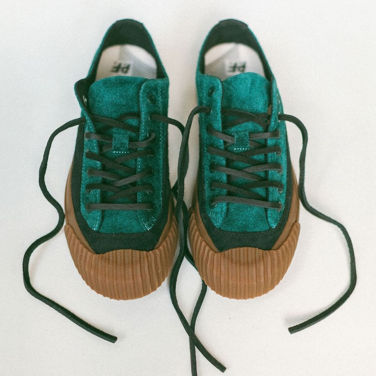 Pair of green sneakers with gum soles on a white background