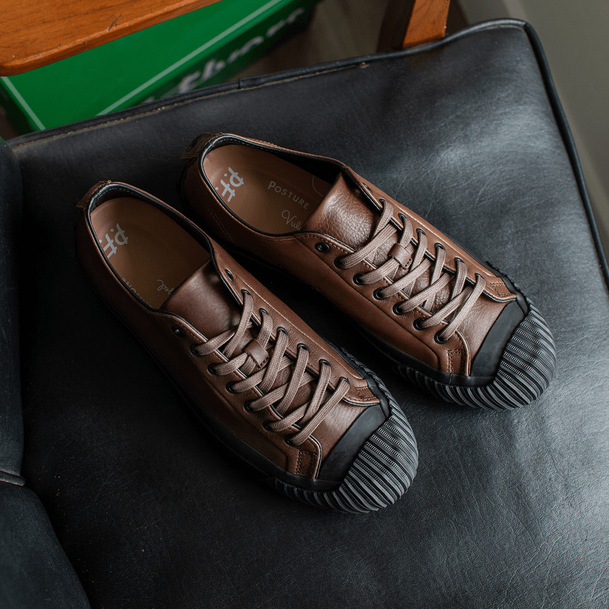 Brown leather low-top sneakers on a chair.