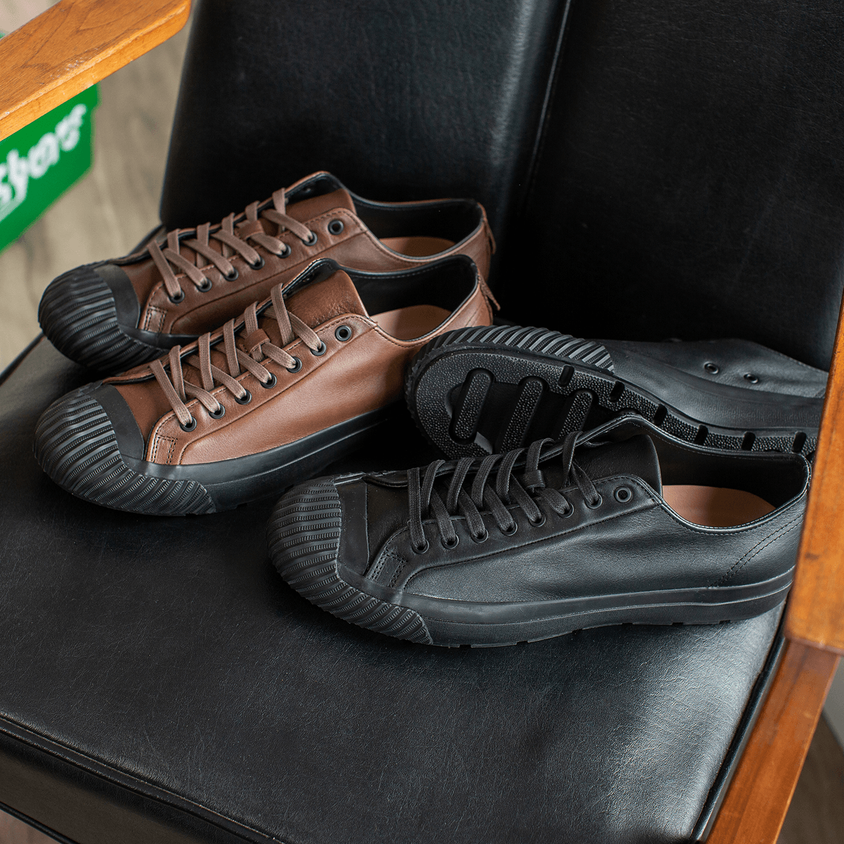Pair of brown and black leather low-top sneakers on a black chair.