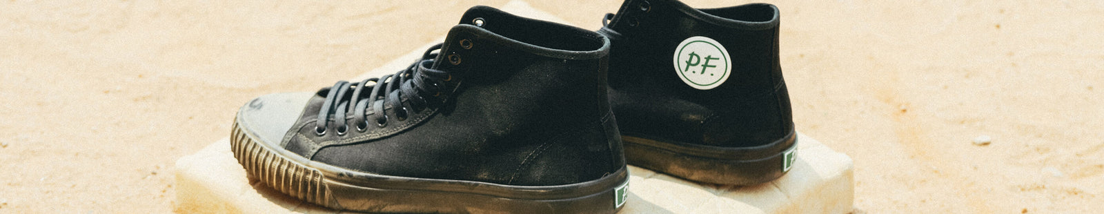 Pair of black high-top sneakers on a baseball base.