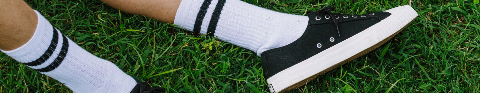 Black low-top sneakers with white soles on grass.