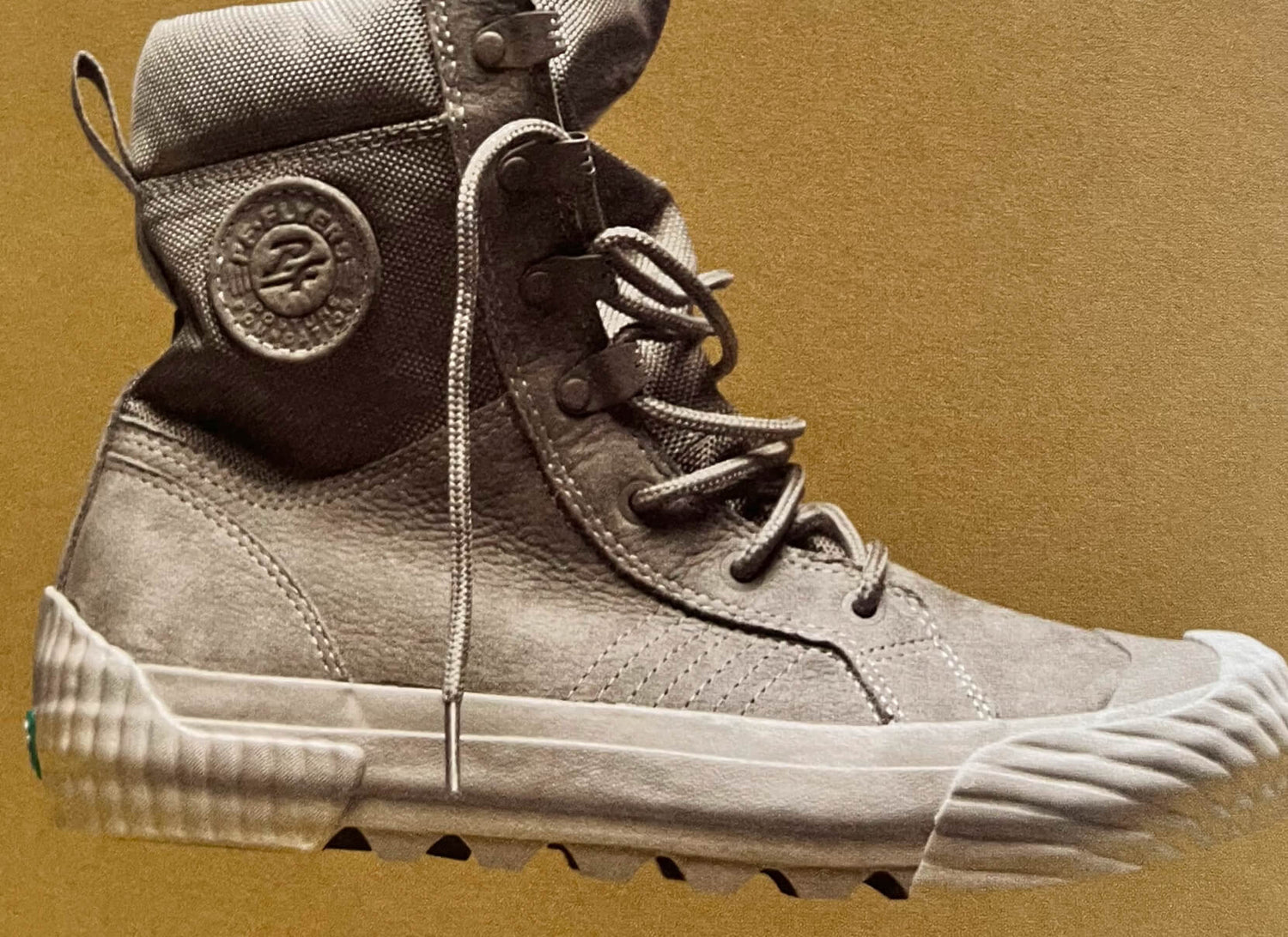 Gray retro high-top P.F. Flyers sneaker against a tan background.