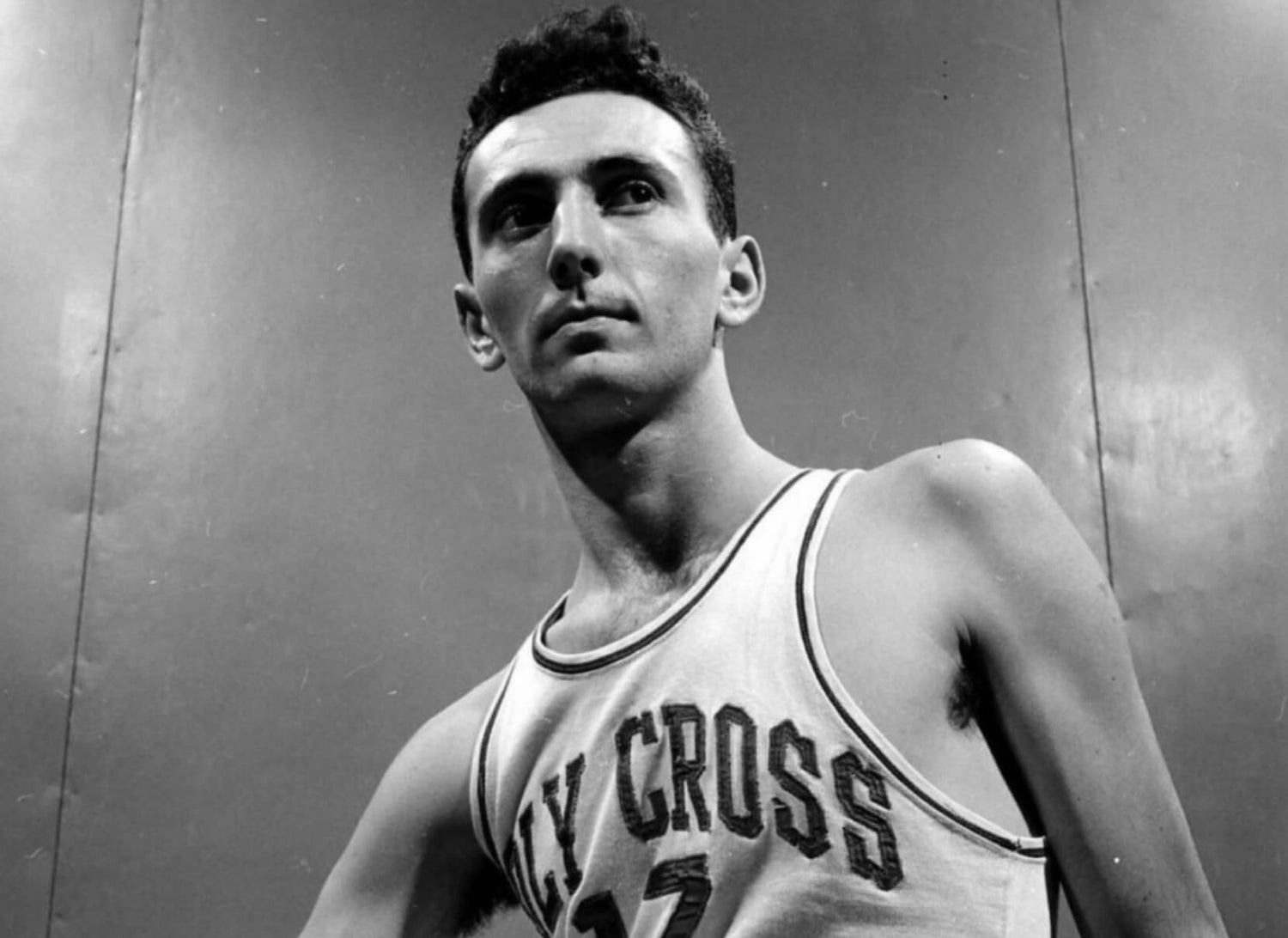 Black-and-white photo of basketball player Bob Cousy wearing a “Holy Cross” jersey.