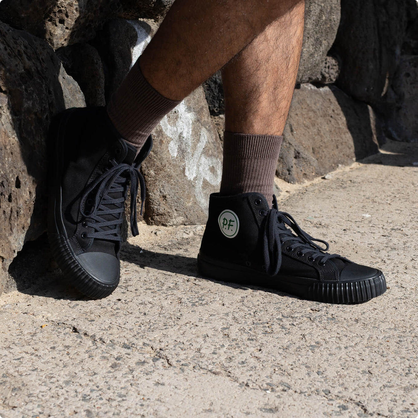 Person wearing black high-top standing on a concrete surface.