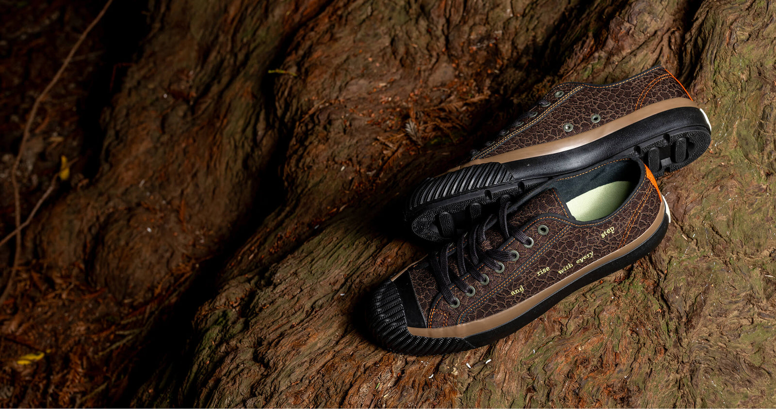 Brown low-top sneakers with black soles on a wooden surface.